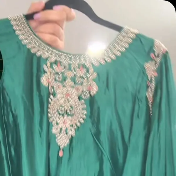 Close-up of a teal neckline with embroidery and stones