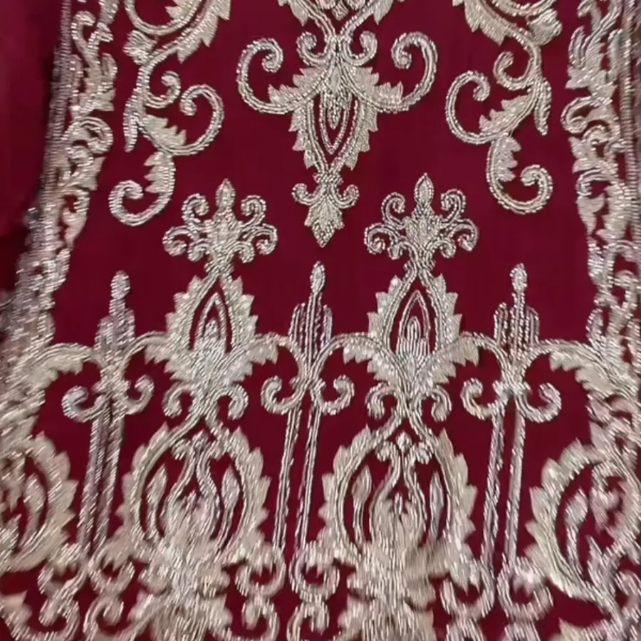 Close view of a maroon suit covered in cream and silver embroidery