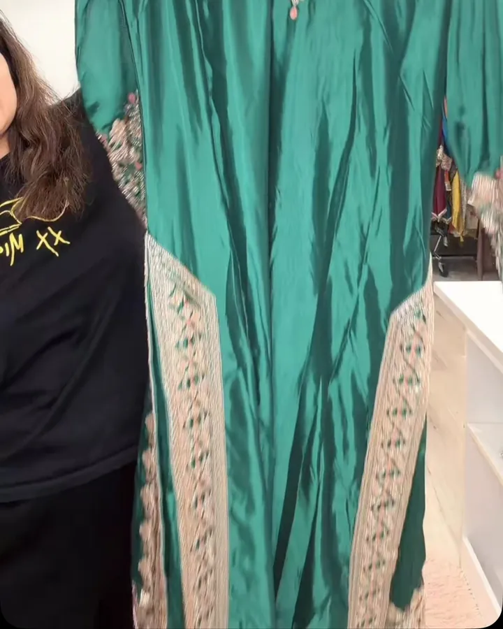 Teal suit with embroidered side panels held up in the boutique
